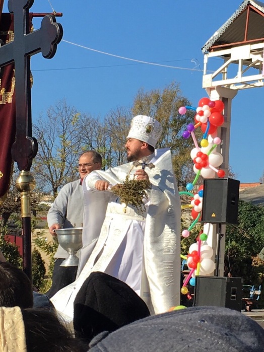 One of the priests uses herbs to fling holy water on the crowd, blessing us.