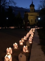 Luminaries light the path to the church at twilight.